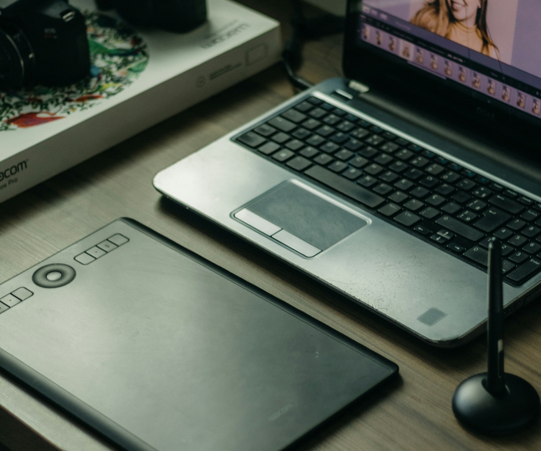 木のデスクでノートやタブレット、ノートパソコンを使いながら制作を進める手元